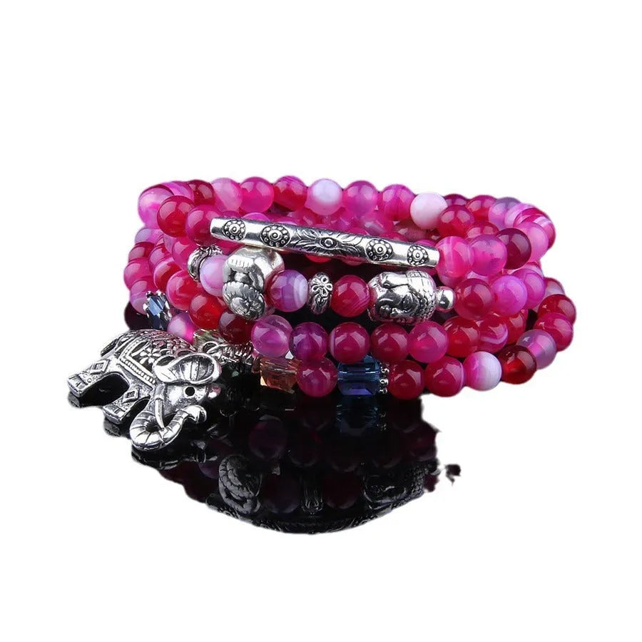 Multi-layer agate bracelet with blue elephant pattern amulet on a wrist.