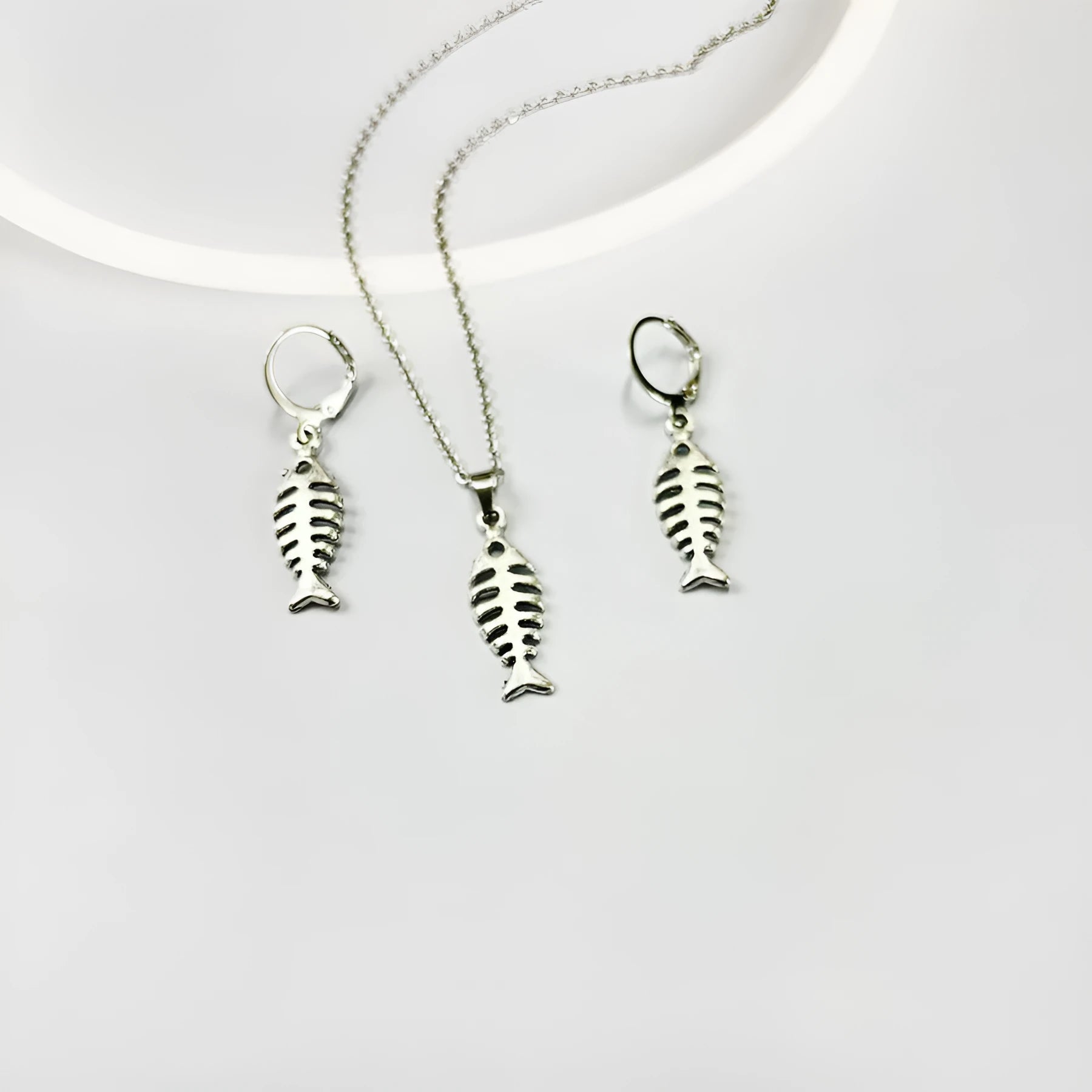 Fishbone pendant necklace and matching earrings set with adjustable chain on grey background