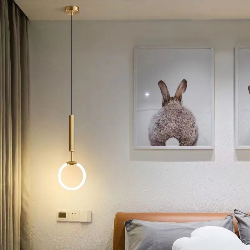 Modern Nordic-style U-shaped metal pendant light with a long black cable, hung above a bedside table.