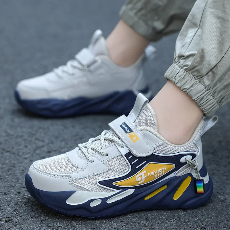 Boy's blue sports running shoe with velcro strap and mesh upper on a hard ground surface.