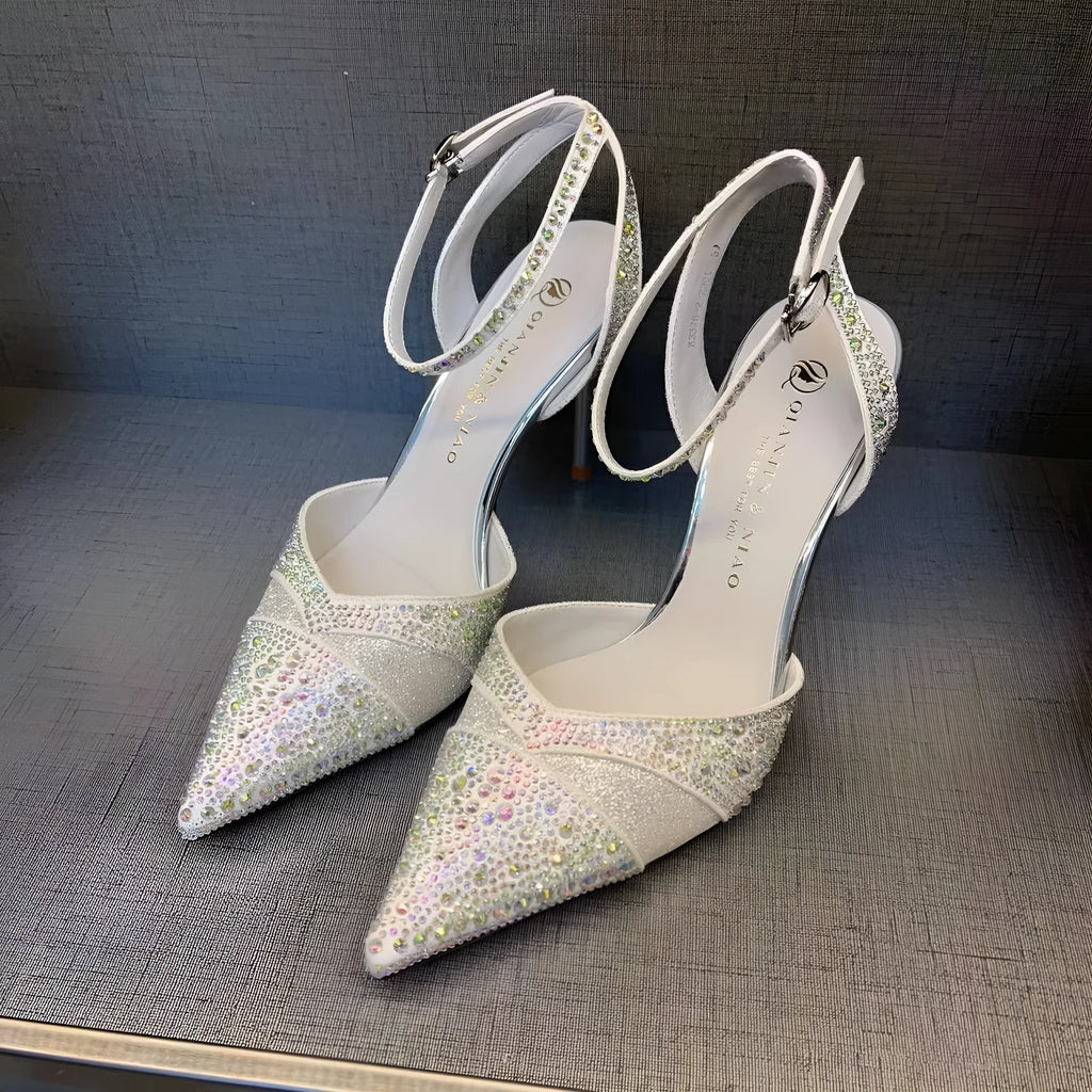 Women's silver and black hollow stiletto high heels with pointed toe and red sole on a plain background.