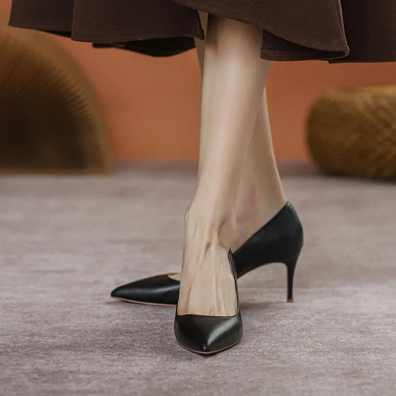 Black pointed-toe high heel pump with a stiletto heel on a plain background.