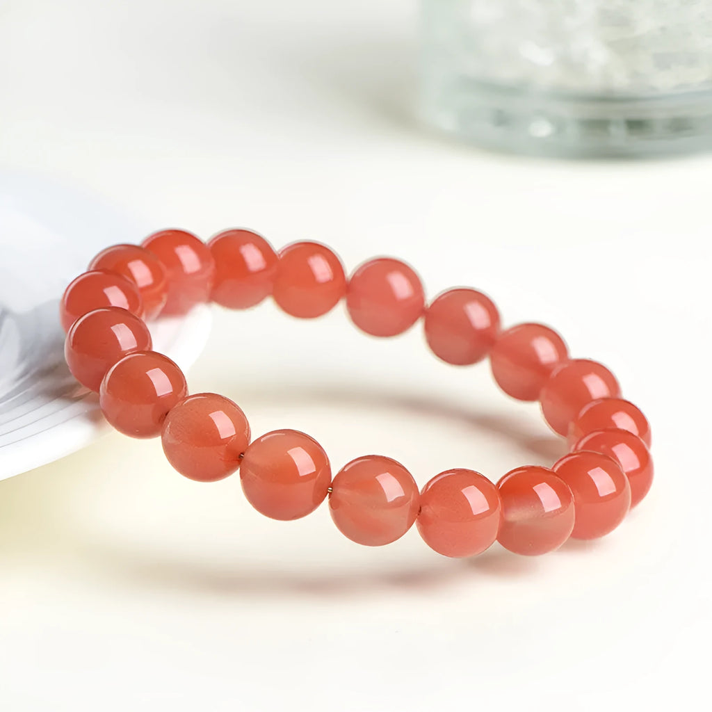 Natural cherry red agate beaded bracelet shown in a single loop, with polished round stones.