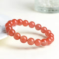 Natural cherry red agate beaded bracelet shown in a single loop, with polished round stones.
