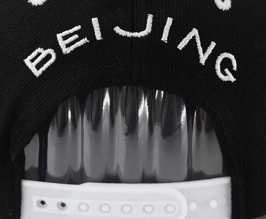 Adjustable black cotton baseball cap with white letter embroidery on the front, showing dome crown shape.