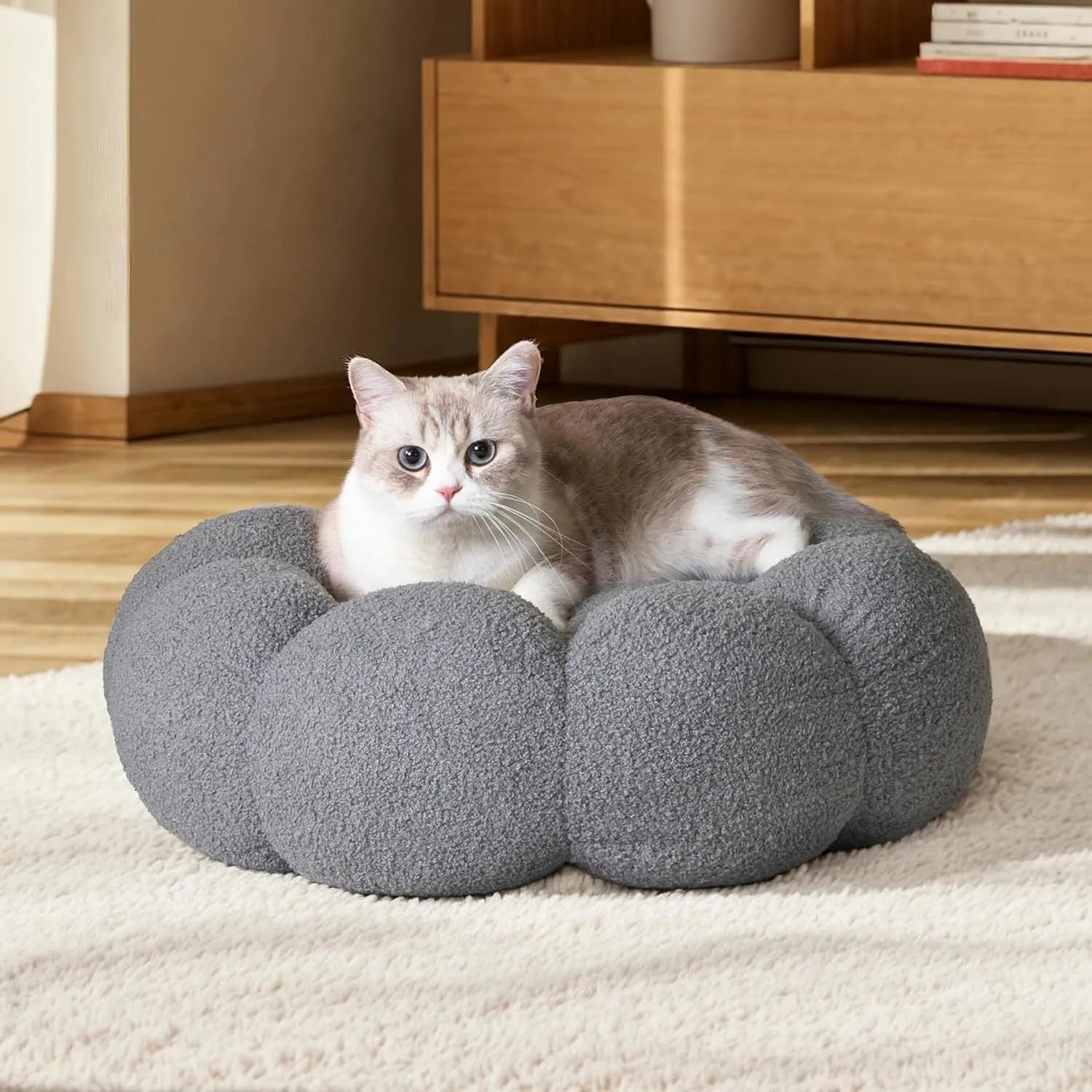 White fluffy flower-shaped pet bed with raised teddy fleece edges and round donut design on a light floor