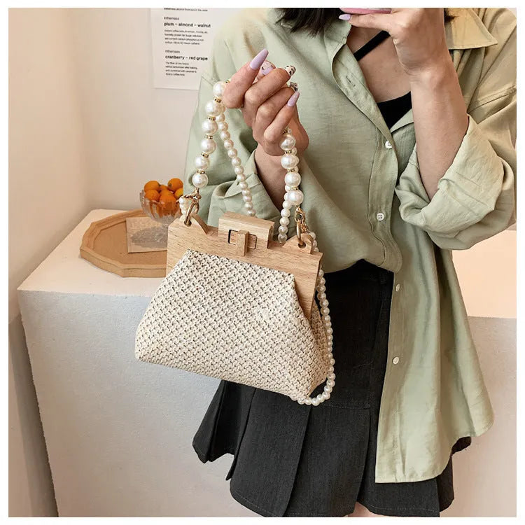 Women's woven straw shoulder bag with pearl chain detail showing horizontal square shape and multiple internal pockets