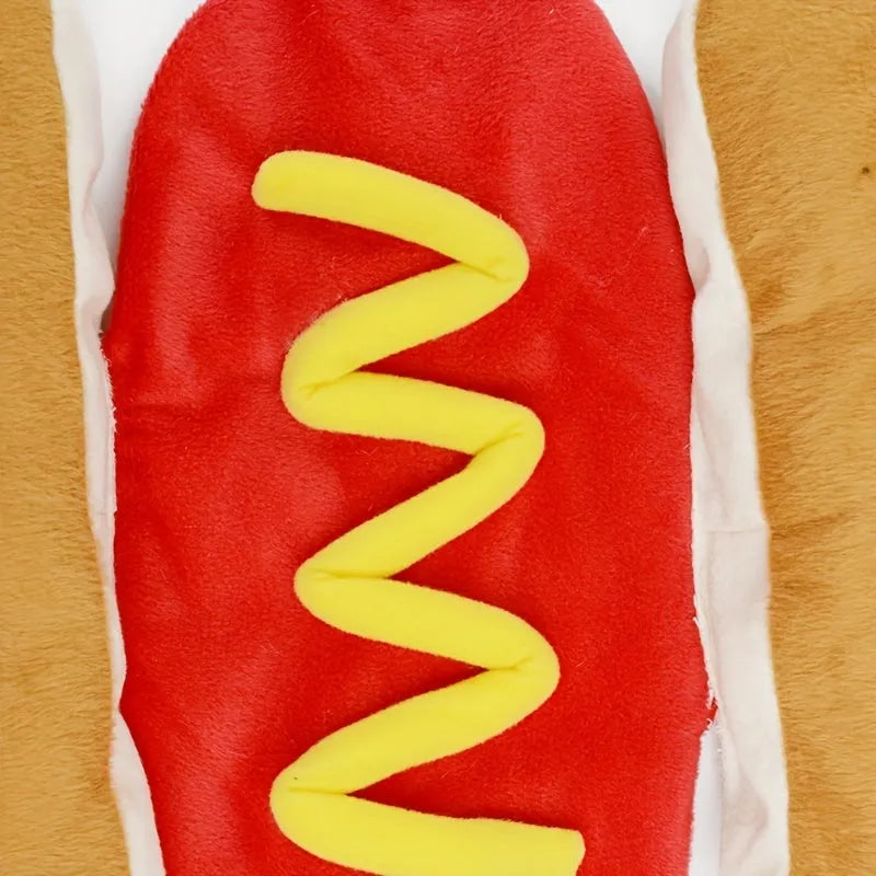 A small dog wearing a red and brown plush hot dog costume with a hood and leg openings.