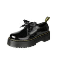 Women's black leather shoes with a thick sole, cross straps, and ribbon laces laid flat.