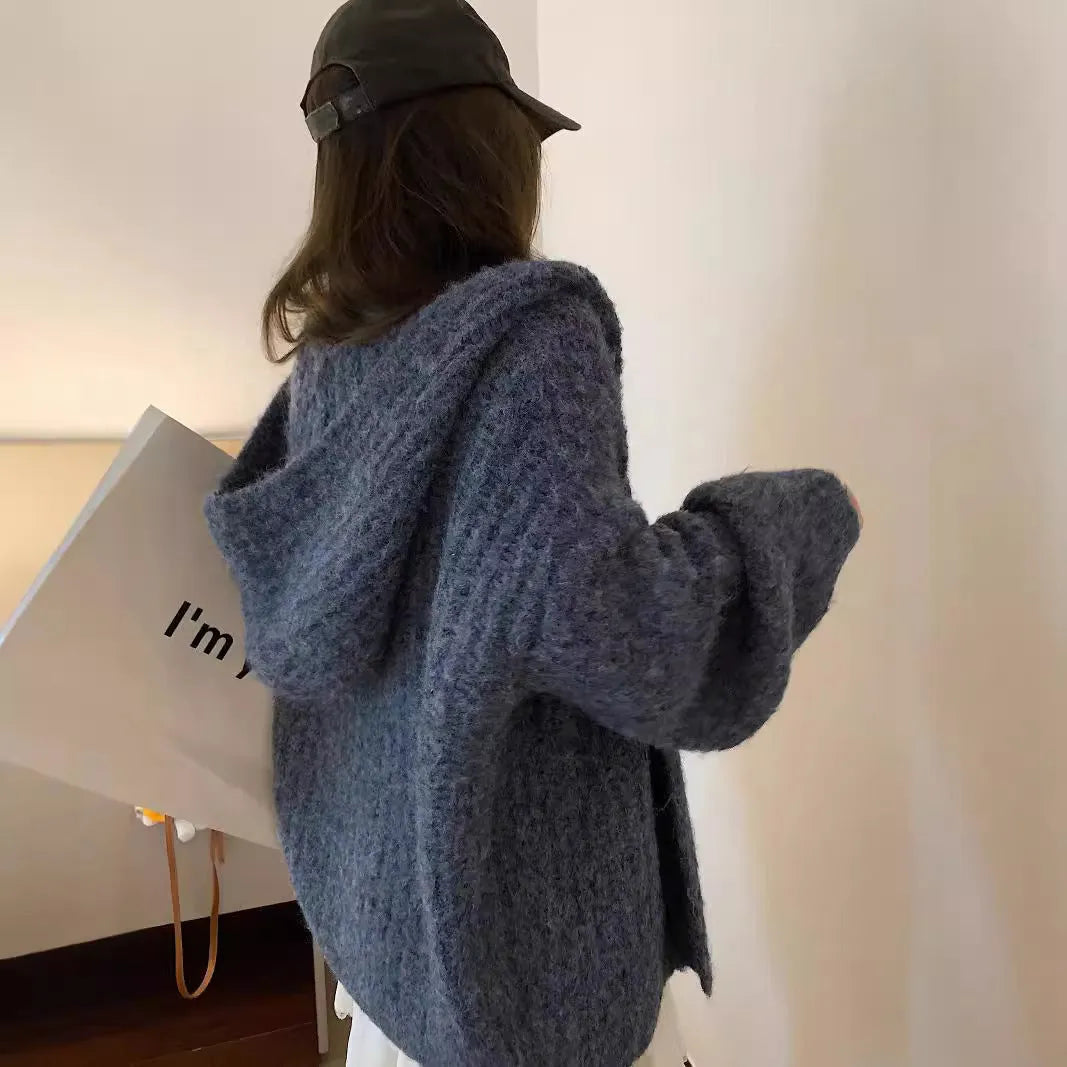Woman wearing a brown retro-style chunky knit hooded cardigan with a loose fit.