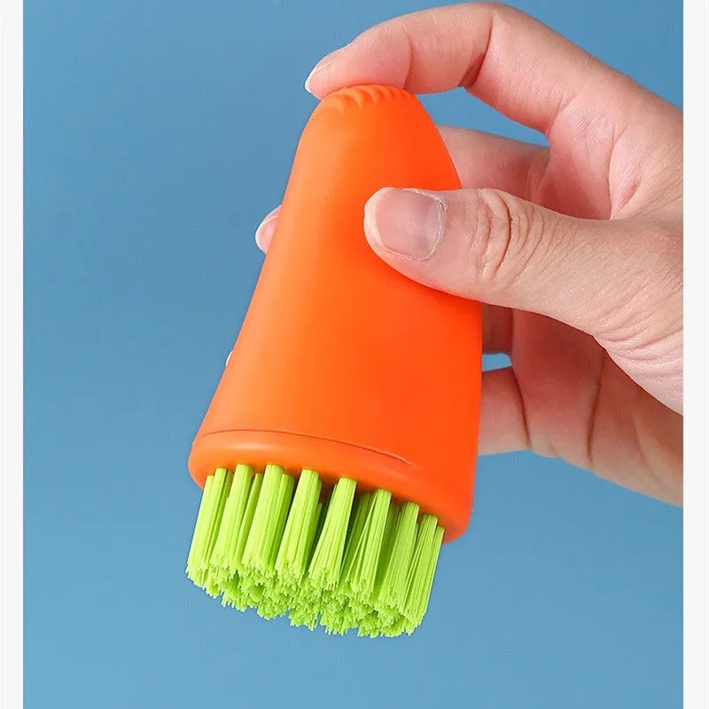 Orange and white carrot-shaped nylon kitchen cleaning brush on a plain background.