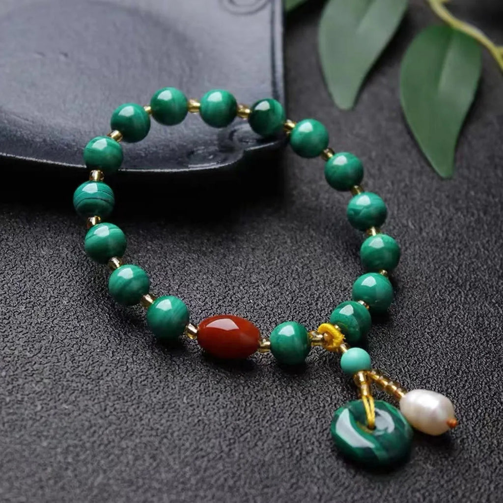 Handmade natural malachite and red agate bracelet with 7-8mm barrel beads on a wrist.