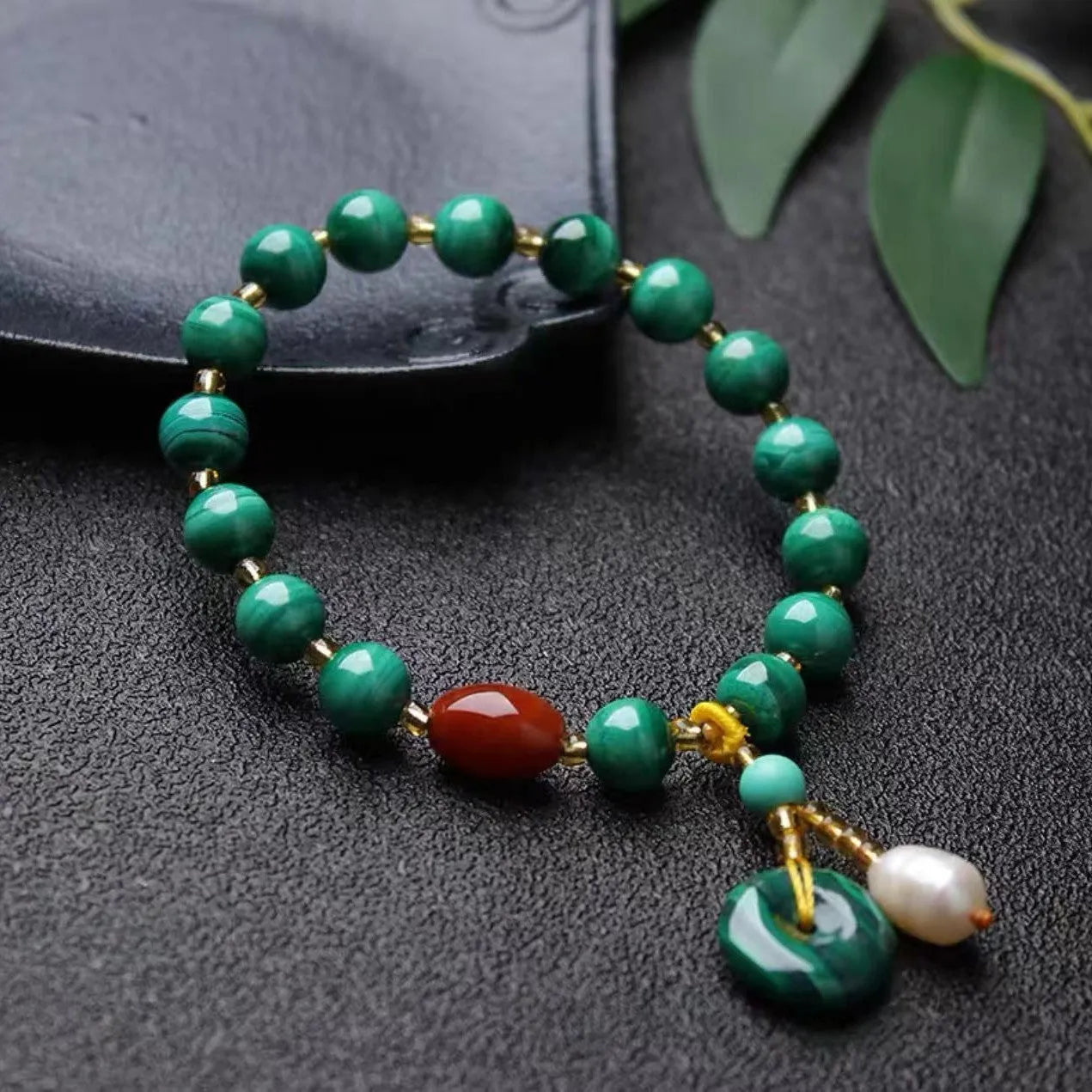 Handmade natural malachite and red agate bracelet with 7-8mm barrel beads on a wrist.