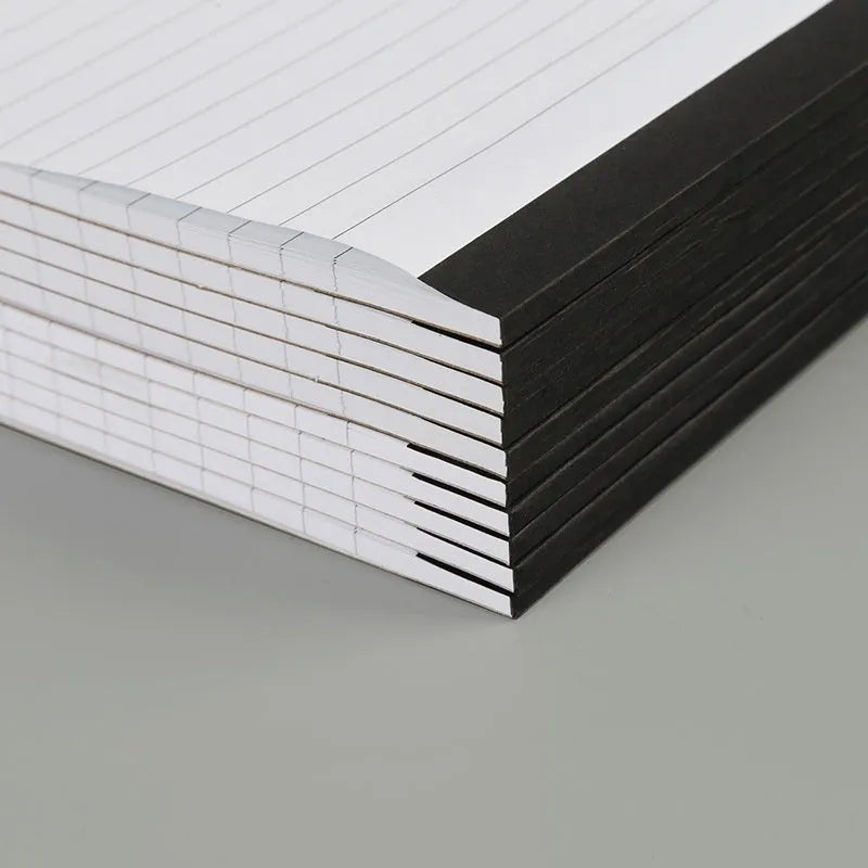 A4 wire-o bound tear-off notepad open on a table, showing ivory white grid pages.