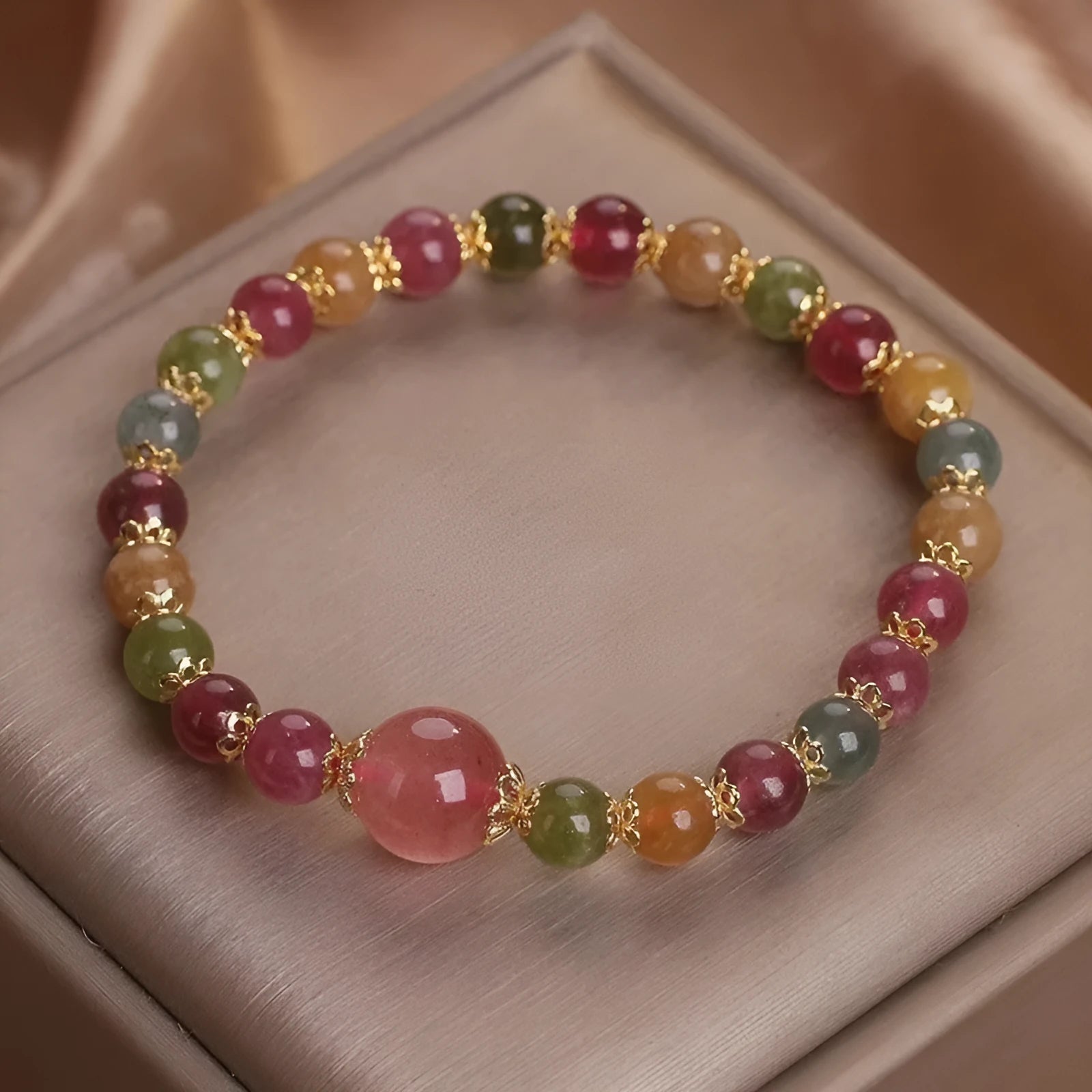 Close-up of a beaded bracelet with round strawberry quartz and tourmaline stones, 10mm in size.