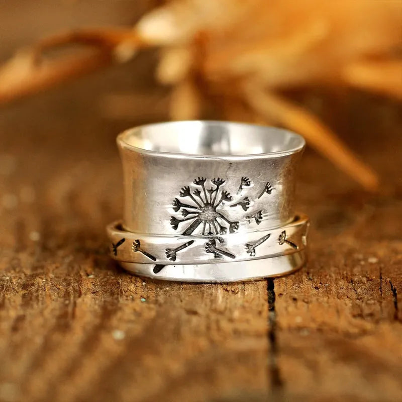 Silver rotating flower ring with movable petals on a finger, showing the kinetic jewellery design