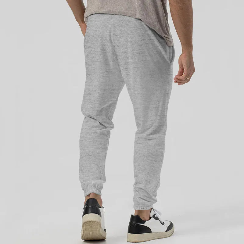 Man wearing grey loose tapered track sweatpants with a micro-elastic cotton blend fabric.