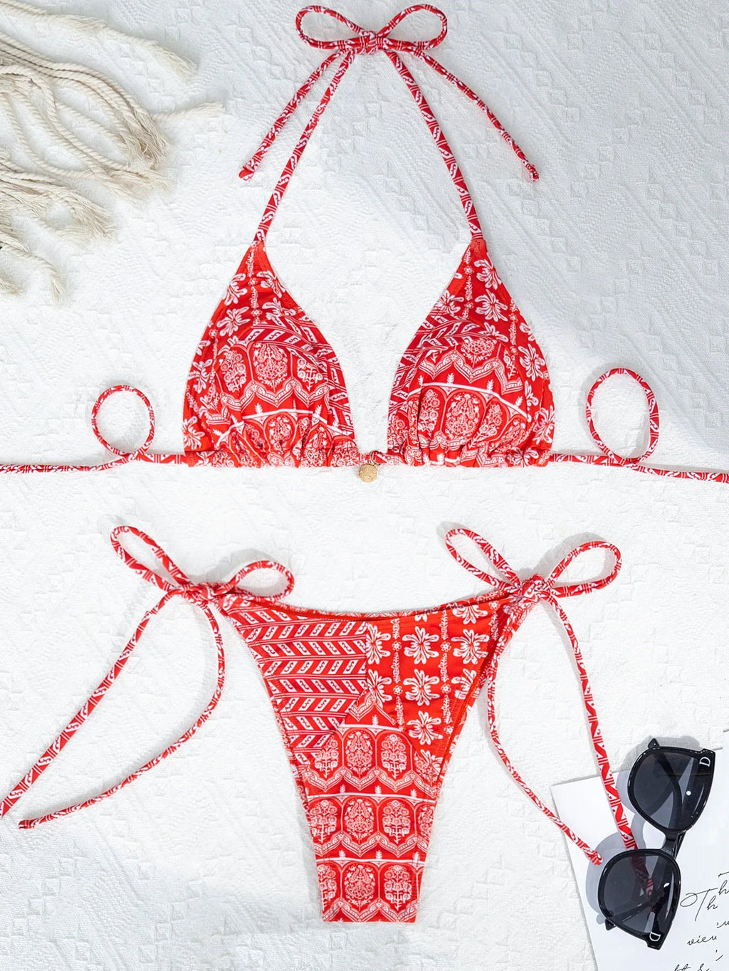 Women's green split bikini swimsuit with bandage-style stitching on a beach.