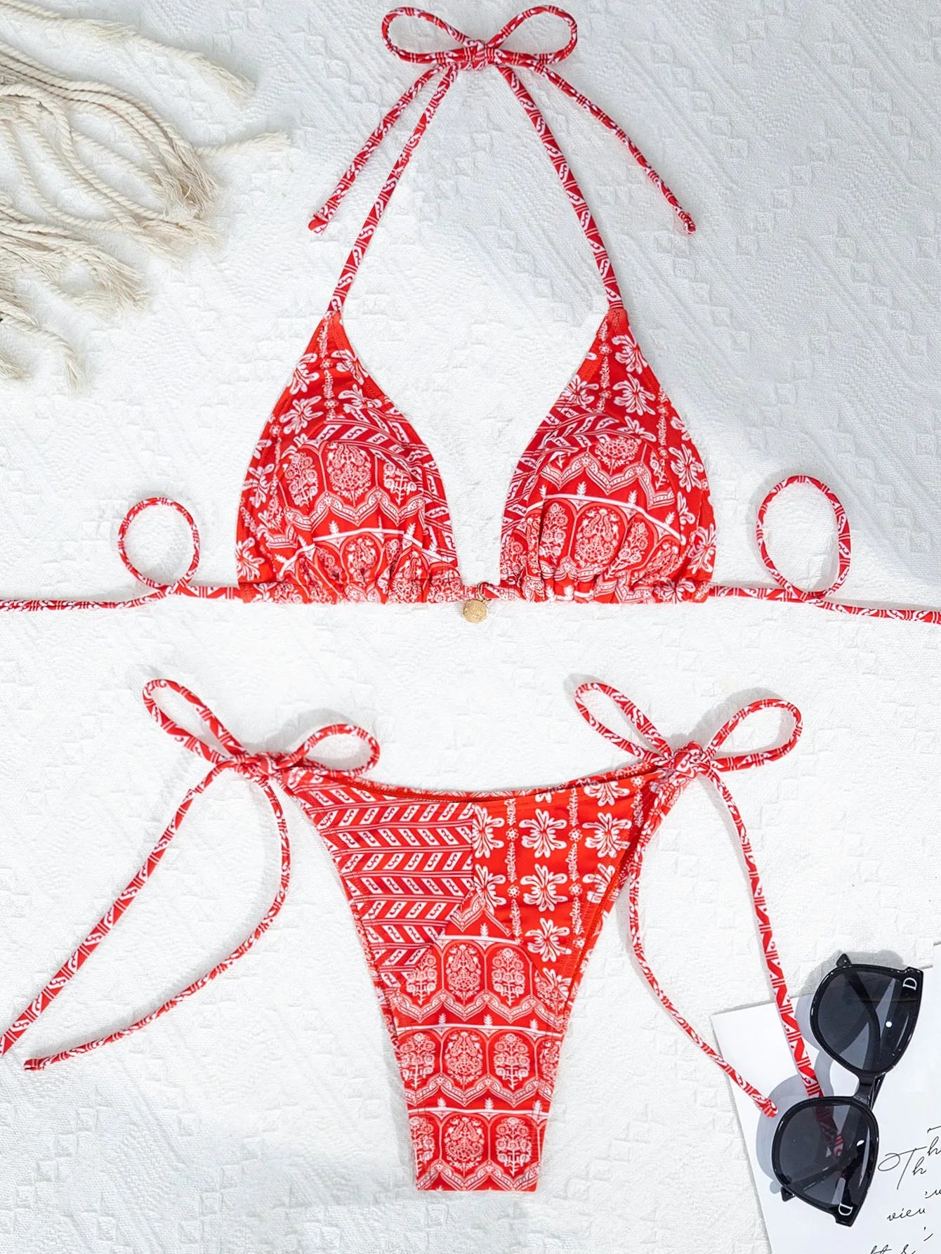 Women's green split bikini swimsuit with bandage-style stitching on a beach.