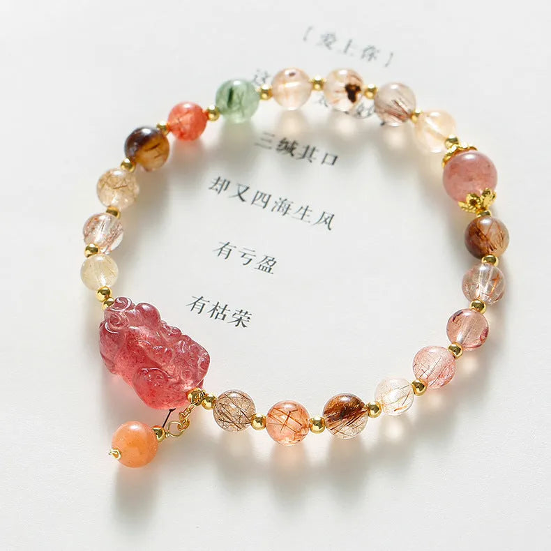 Close-up of a women's copper bracelet with a pink Strawberry Quartz crystal, a detailed Pixiu charm, and a white freshwater pearl.