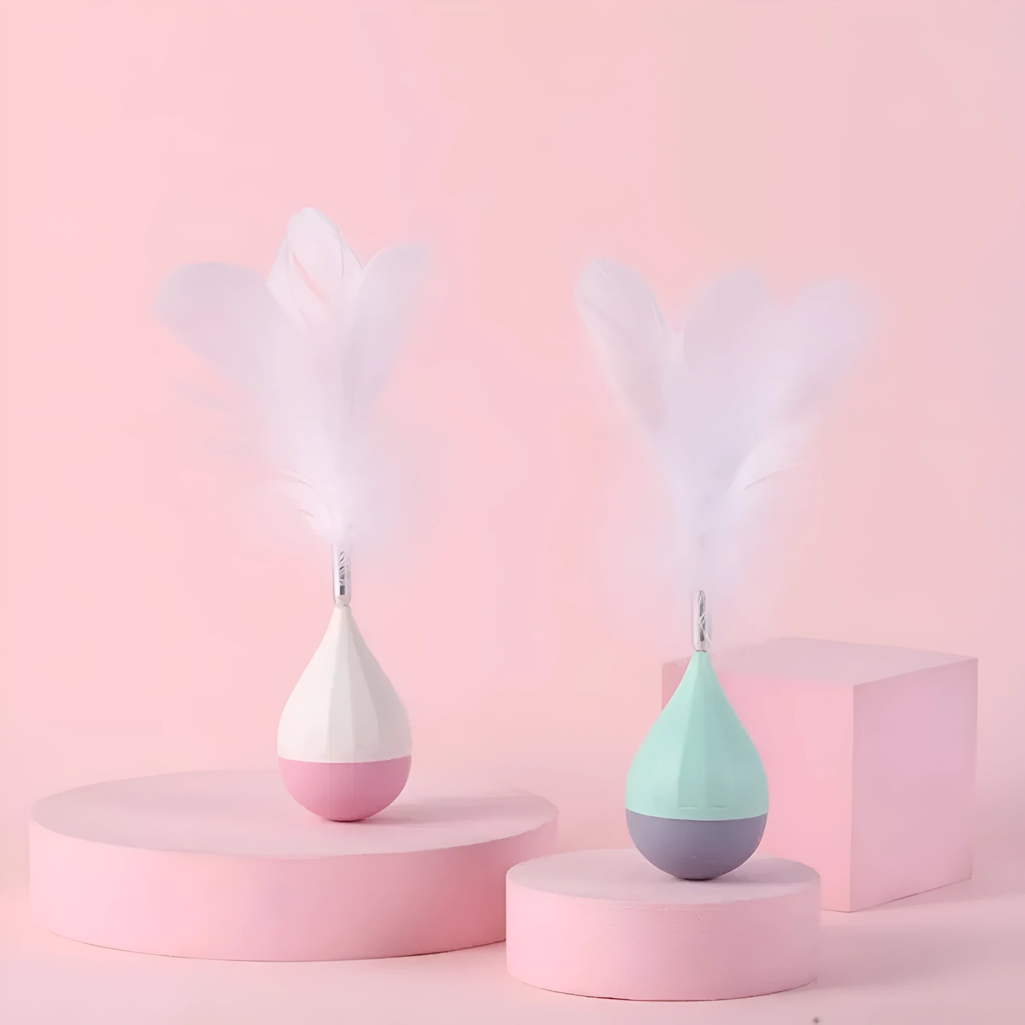 Feather tumbler cat toy with rolling ball and goose feather tease stick on a coloured background.