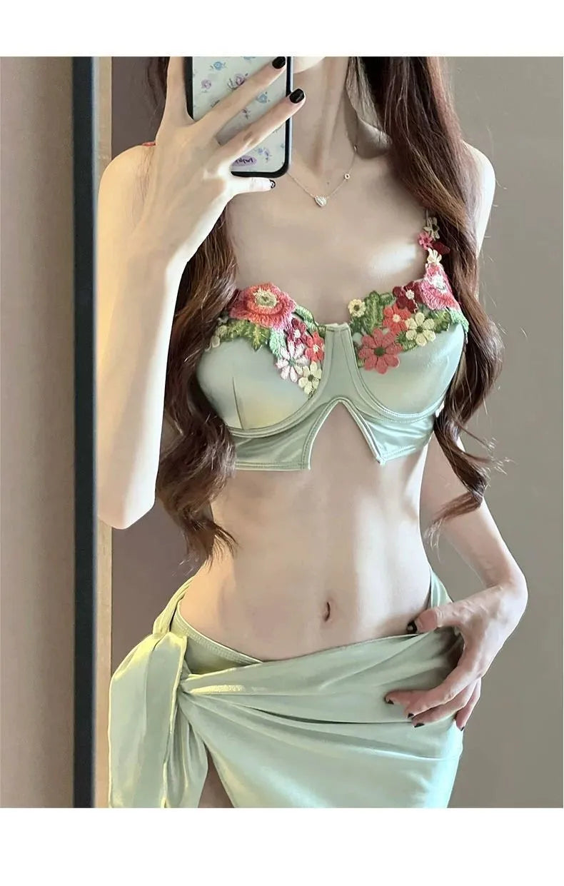 Green women's three-piece bikini set showing sleeveless triangle top, briefs, and a skirt on a mannequin.
