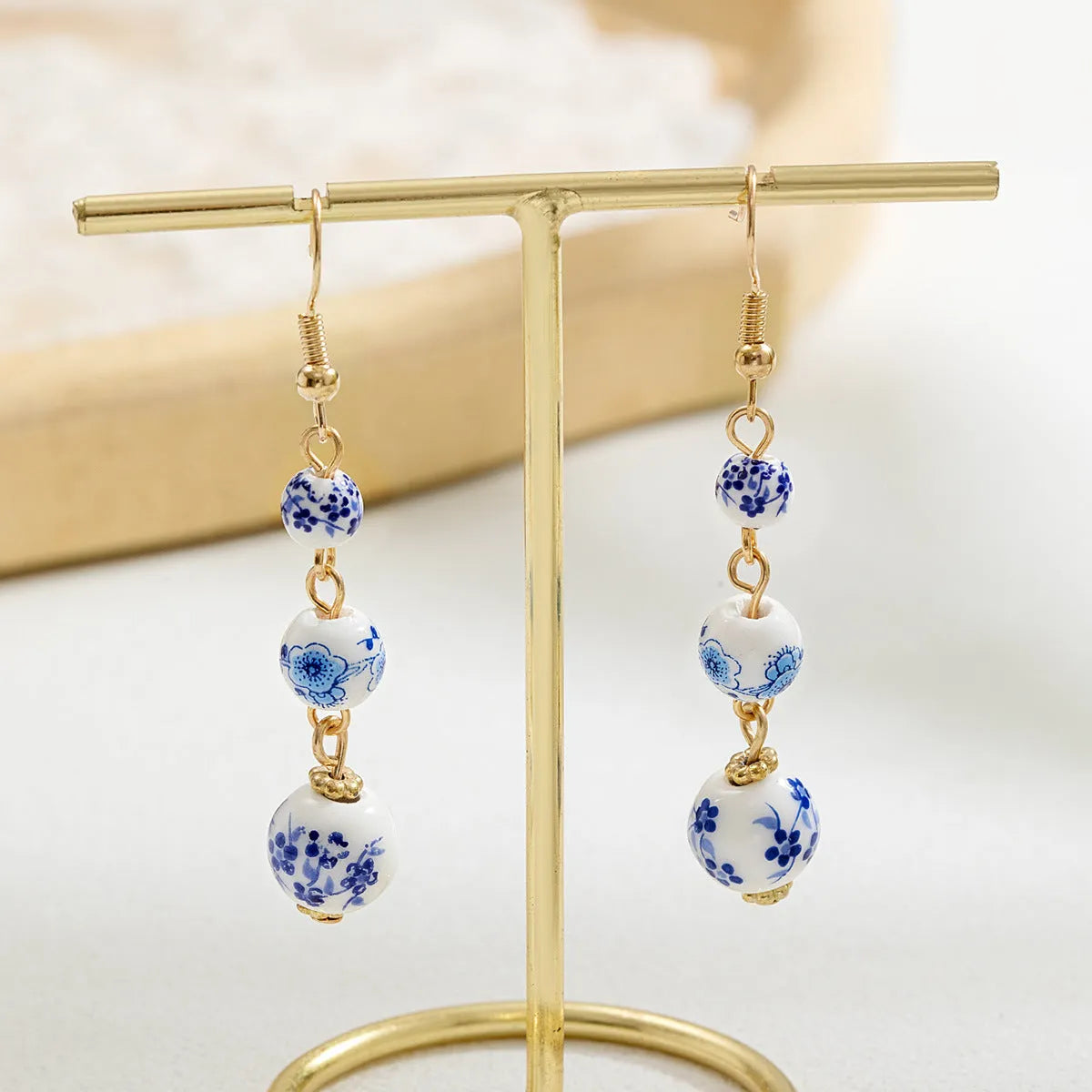 Long blue and white porcelain ceramic bead earrings with geometric alloy details on a white background.