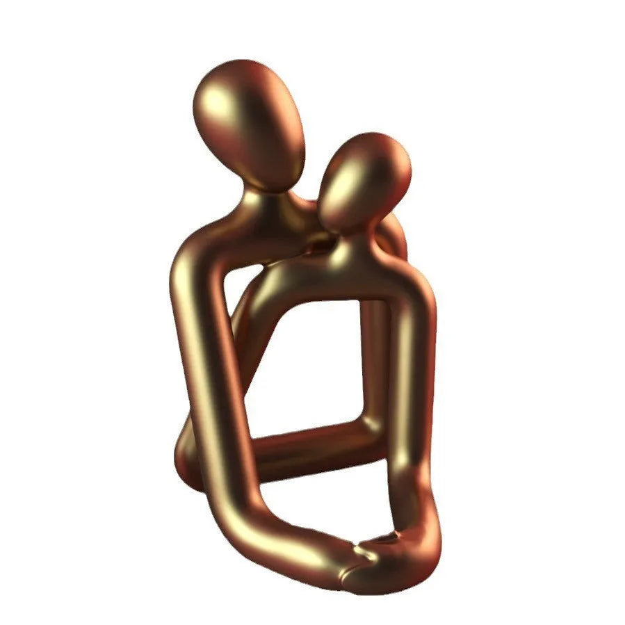 Modern resin couple statue in milky white or gold colour on a wooden surface.